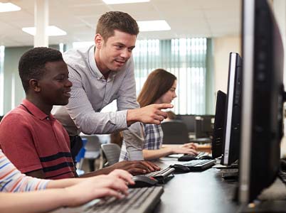 Photo of a teacher helping students learn on a computer